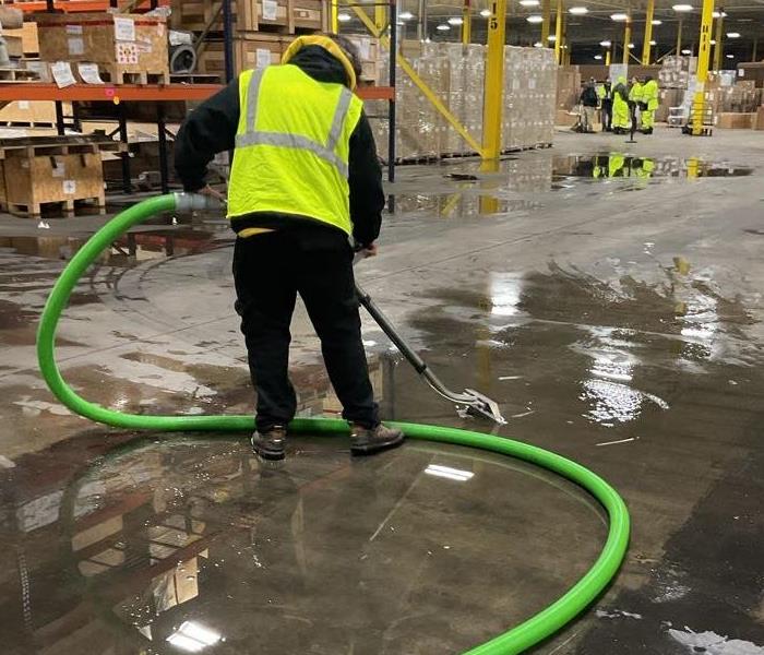 MAN EXTRACTING WATER FROM WAREHOUSE FLOOR